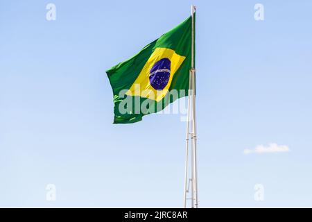 Goiânia, Goias, Brasilien – 23. August 2022: Die Flagge Brasiliens. Die Flagge Brasiliens fliegt, flattert im Wind und der blaue Himmel im Hintergrund. Stockfoto