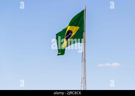 Goiânia, Goias, Brasilien – 23. August 2022: Die Flagge Brasiliens. Die Flagge Brasiliens fliegt, flattert im Wind und der blaue Himmel im Hintergrund. Stockfoto