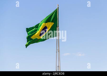Goiânia, Goias, Brasilien – 23. August 2022: Die Flagge Brasiliens. Die Flagge Brasiliens fliegt, flattert im Wind und der blaue Himmel im Hintergrund. Stockfoto