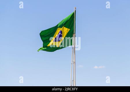 Goiânia, Goias, Brasilien – 23. August 2022: Die Flagge Brasiliens. Die Flagge Brasiliens fliegt, flattert im Wind und der blaue Himmel im Hintergrund. Stockfoto