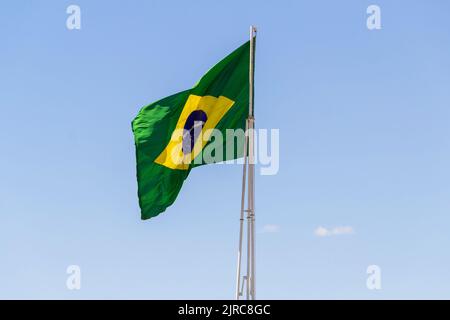Goiânia, Goias, Brasilien – 23. August 2022: Die Flagge Brasiliens. Die Flagge Brasiliens fliegt, flattert im Wind und der blaue Himmel im Hintergrund. Stockfoto