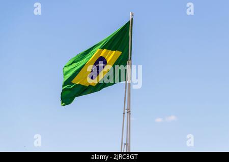 Goiânia, Goias, Brasilien – 23. August 2022: Die Flagge Brasiliens. Die Flagge Brasiliens fliegt, flattert im Wind und der blaue Himmel im Hintergrund. Stockfoto