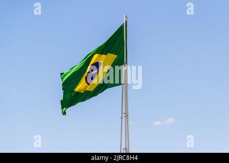 Goiânia, Goias, Brasilien – 23. August 2022: Die Flagge Brasiliens. Die Flagge Brasiliens fliegt, flattert im Wind und der blaue Himmel im Hintergrund. Stockfoto
