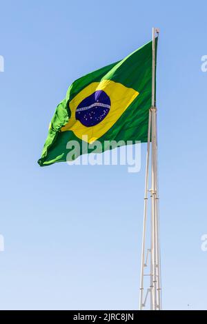 Goiânia, Goias, Brasilien – 23. August 2022: Die Flagge Brasiliens. Die Flagge Brasiliens fliegt, flattert im Wind und der blaue Himmel im Hintergrund. Stockfoto