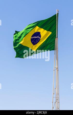 Goiânia, Goias, Brasilien – 23. August 2022: Die Flagge Brasiliens. Die Flagge Brasiliens fliegt, flattert im Wind und der blaue Himmel im Hintergrund. Stockfoto