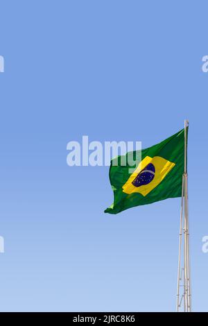 Goiânia, Goias, Brasilien – 23. August 2022: Die Flagge Brasiliens. Die Flagge Brasiliens fliegt, flattert im Wind und der blaue Himmel im Hintergrund. Stockfoto