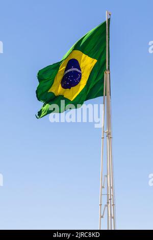 Goiânia, Goias, Brasilien – 23. August 2022: Die Flagge Brasiliens. Die Flagge Brasiliens fliegt, flattert im Wind und der blaue Himmel im Hintergrund. Stockfoto