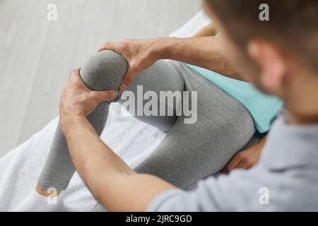 Physiotherapeut oder Chiropraktiker in der Physiotherapie-Klinik, die das Knie des Patienten untersucht Stockfoto