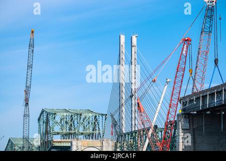 Eine alte Brücke wird gerade abgerissen, neben einer neuen Brücke mit Kabelgestasten. Stockfoto