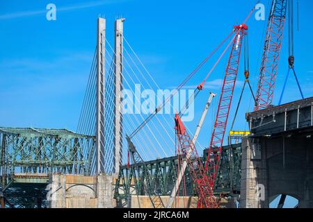 Eine alte Brücke wird gerade abgerissen, neben einer neuen Brücke mit Kabelgestasten. Stockfoto