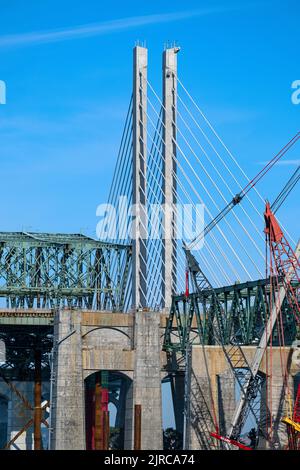 Eine alte Brücke wird gerade abgerissen, neben einer neuen Brücke mit Kabelgestasten. Stockfoto