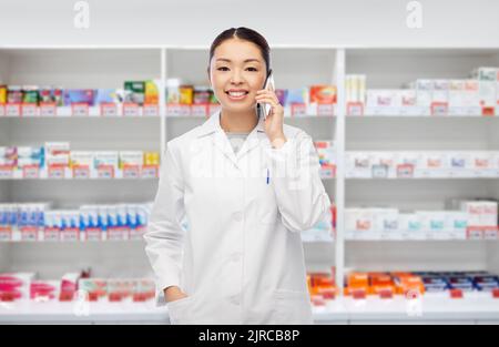 asiatischer Apotheker, der bei der Apotheke telefoniert Stockfoto