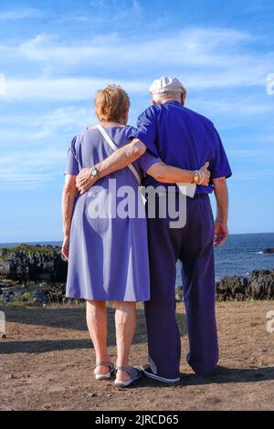Ein älteres Paar umarmt den Himmel schauend Stockfoto