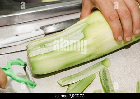 Rezept für Zucchini-Krapfen. Schritt 1 - die Zucchini schälen. Die Hände schälen grüne Zucchini mit einem Gemüseschäler. Stockfoto