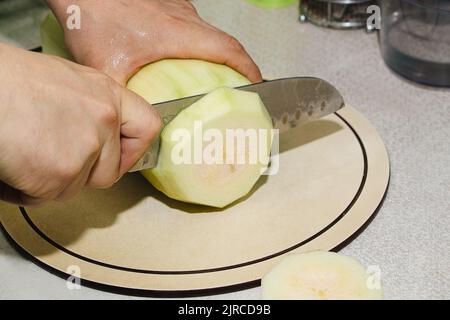 Rezept für Zucchini-Krapfen. Schritt 2 - Zucchini schneiden. Hände schneiden grüne Zucchini in Würfel. Kochen veganer Gemüsepfannkuchen. Stockfoto