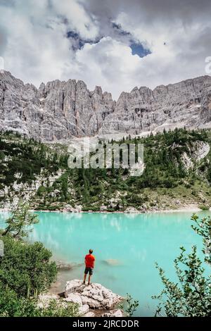 Männliche Backpacker genießen türkisfarbenen Lago di Sorapiss Bergsee, Dolomiten Berge, Italien. Aktive Menschen in der Natur. Kalksteingipfel, Schluchten, Kristall Stockfoto