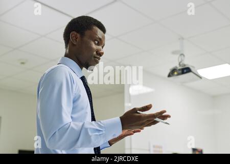 Minimale Seitenansicht Porträt von jungen schwarzen Lehrer, der Vortrag in der Klasse und gestikulieren, kopieren Raum Stockfoto