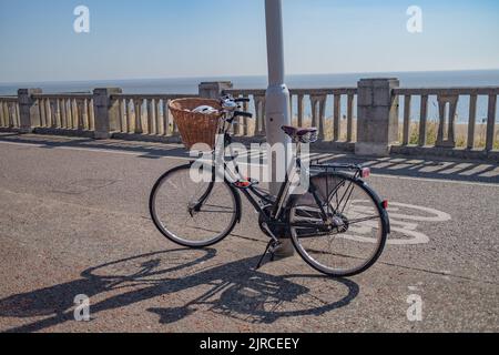 Das Damenfahrrad wurde an einem Laternenpfahl an der Strandpromenade in der Stadt Lowestoft in Suffolk verriegelt und angekettet Stockfoto