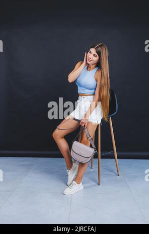 Hübsche junge Frau in weißen Shorts und weißen Leder-Sneakers. Damenmode im Sommer Stockfoto