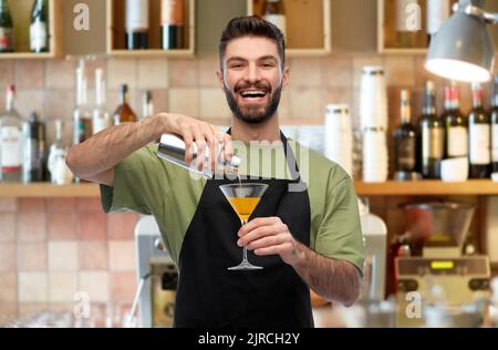 Glücklicher Barkeeper mit Shaker und Glas, der das Getränk zubereitete Stockfoto