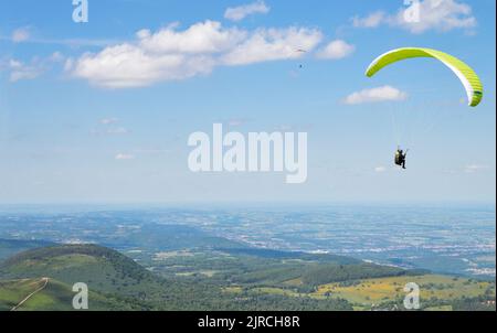 Ein Gleitschirmflieger, der über vulkanische Berge fliegt. Es ist ein Extremsport. Stockfoto