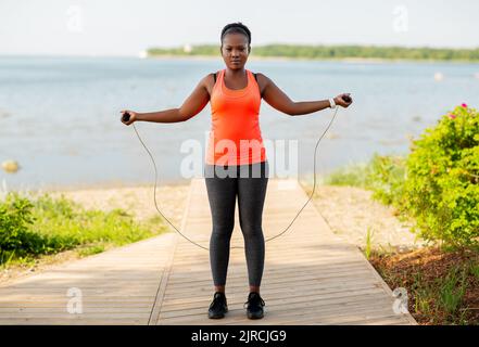 afrikanische Frau trainiert am Strand mit Springseil Stockfoto