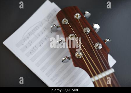 Nahaufnahme des akustischen Gitarrenkopfes mit Musikbuch Stockfoto