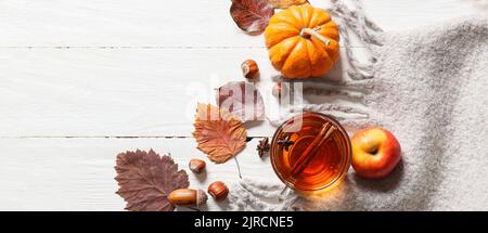 Komposition mit Tasse Tee, Herbstblättern, Kürbis und Schal auf weißem Holzhintergrund, Draufsicht Stockfoto