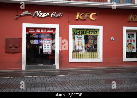 Puebla City, Puebla, Mexiko - 08 2022. August: Pizza Hut und KFC teilen sich das gleiche Gebäude mit einer roten Mauer in Puebla City, Mexiko. Stockfoto