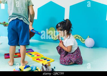 Vorschulkinder, die im Kindergarten mit ihrer Lehrerin mit Farben spielen. Hochwertige Fotos Stockfoto