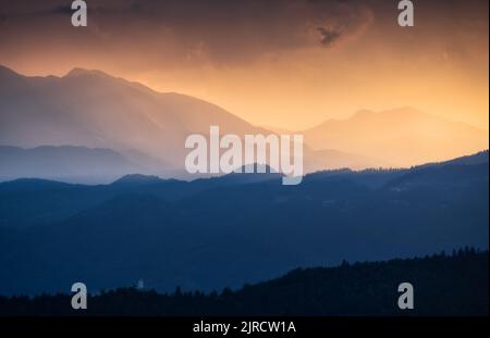 Erstaunliche Silhouetten von Bergen bei farbenfrohem Sonnenuntergang im Sommer Stockfoto