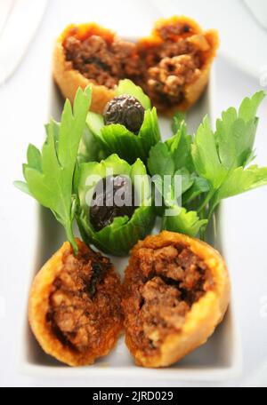 Gefüllte Fleischbällchen (türkisch: Isli Kofte) mit Oliven auf dem Speiseteller. Stockfoto