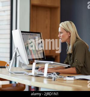 Hart an der Arbeit und Planung für langfristigen Erfolg. Eine reife Geschäftsfrau, die an einem Computer in einem Büro arbeitet. Stockfoto