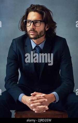 Ein Gentleman zu sein, zeigt sich in deinem Aussehen. Studioaufnahme eines gut gekleideten Geschäftsmanns vor grauem Hintergrund. Stockfoto