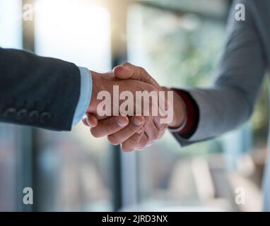 Zusammenführen für den Erfolg. Zwei unkenntliche Geschäftsleute schütteln sich die Hände, nachdem sie einen Deal im Büro gemacht haben. Stockfoto