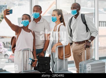 Reisende, die auf ihrer Reise, Reise oder im Urlaub im Ausland Selfie mit kovidierter Gesichtsmaske am Flughafen machen. Gruppe von Personen oder Freunden mit Koffer Stockfoto