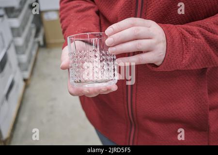 Kaukasisches Mädchen kauft ein transparentes Glas für starke alkoholische Getränke im Laden Stockfoto