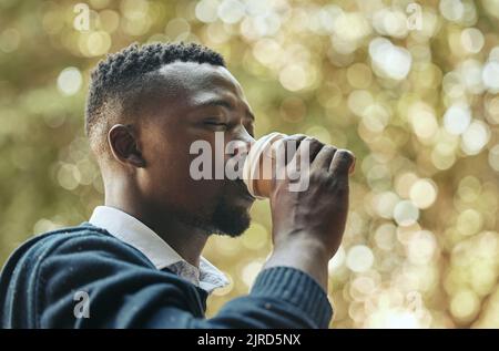 Geschäftsmann mit Getränk Kaffeetasse in einem Park mit Bäumen, Natur und Bokeh Hintergrund. Ruhiger schwarzer Mann, Firmenmitarbeiter oder Mitarbeiter auf Stockfoto