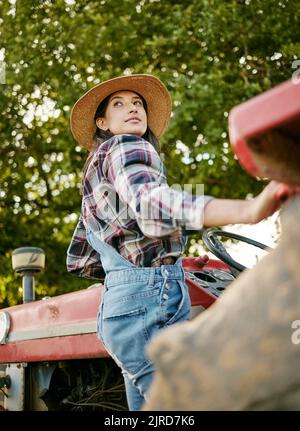 Frau, die während der Erntezeit in der Landwirtschaft arbeitet, oder Landwirtin auf einem Traktor. Nachhaltigkeit Landwirtschaft auf dem Land. Serious Mädchen Landwirtschaft in einem Stockfoto