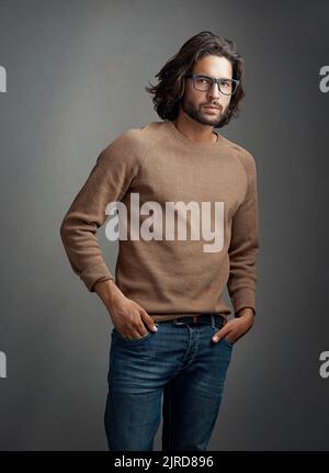 Cool, selbstbewusst und lässig. Studioaufnahme eines hübschen jungen Mannes, der vor einem grauen Hintergrund posiert. Stockfoto