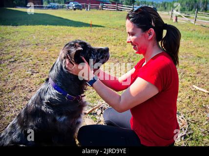 Reife Frau, die einen niedlichen Hund umarmt Stockfoto