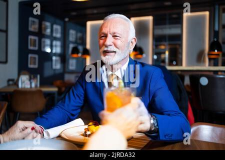 Glücklicher älterer Mann, der in einem Restaurant lächelt und toast Stockfoto