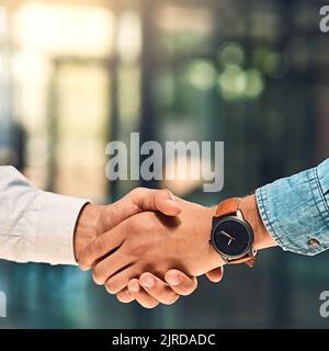 Nun, gemeinsam große Dinge tun. Zwei nicht identifizierbare junge Geschäftspartner schütteln sich im Büro die Hände. Stockfoto