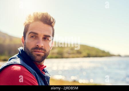 Sammeln seiner Gedanken in der Natur. Ein nachdenklicher Wanderer bewundern den Blick auf einen See an einem sonnigen Tag. Stockfoto