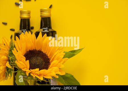 Sonnenblumenöl. Ölflaschen, verstreute schwarze Sonnenblumenkerne und Sonnenblumen auf gelbem Hintergrund.Sonnenblumenkeröl-Mockup. Bio-natürliche Bauernhof Sonnenblume Stockfoto