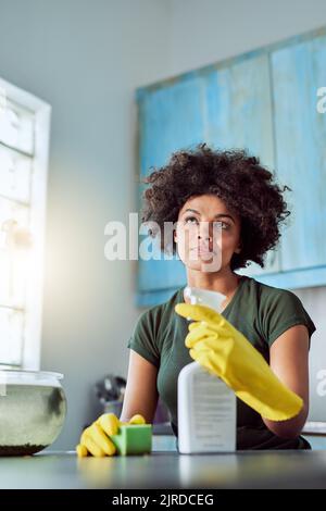 Ich bin fast fertig. Eine attraktive junge Frau mit gelben Handschuhen, die ihr Zuhause putzt. Stockfoto