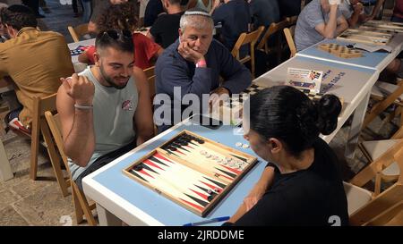 Israelis und Araber spielen ein Backgammon-Tischspiel während des Jerusalem Double Backgammon-Meisterschaftsturniers, das am 23. August 2022 im christlichen Viertel in der Altstadt in Jerusalem, Israel, stattfindet. Backgammon, auch Shesh-besh genannt, stammt aus tausenden von Jahren und wird sowohl von Arabern als auch von Juden gespielt. Stockfoto