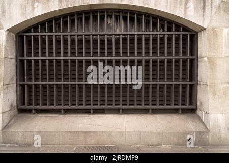 Nahaufnahme des Fensters, das im historischen alten Gebäude als Konzept für Gefängnishaft und Einbruchschutz stark mit einem massiven Metallstahlgitter aus Eisen versperrt ist Stockfoto