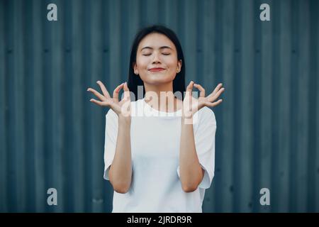 Porträt einer asiatischen Frau mit der Hand okay Gestik gegen blaue Wand Stockfoto