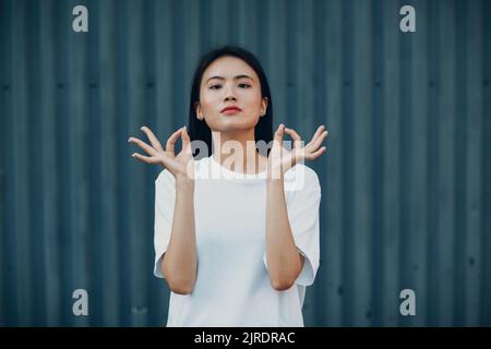 Porträt einer asiatischen Frau mit der Hand okay Gestik gegen blaue Wand Stockfoto